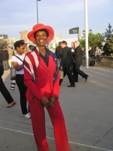 Black woman wearing a red suit and an American flag scarf